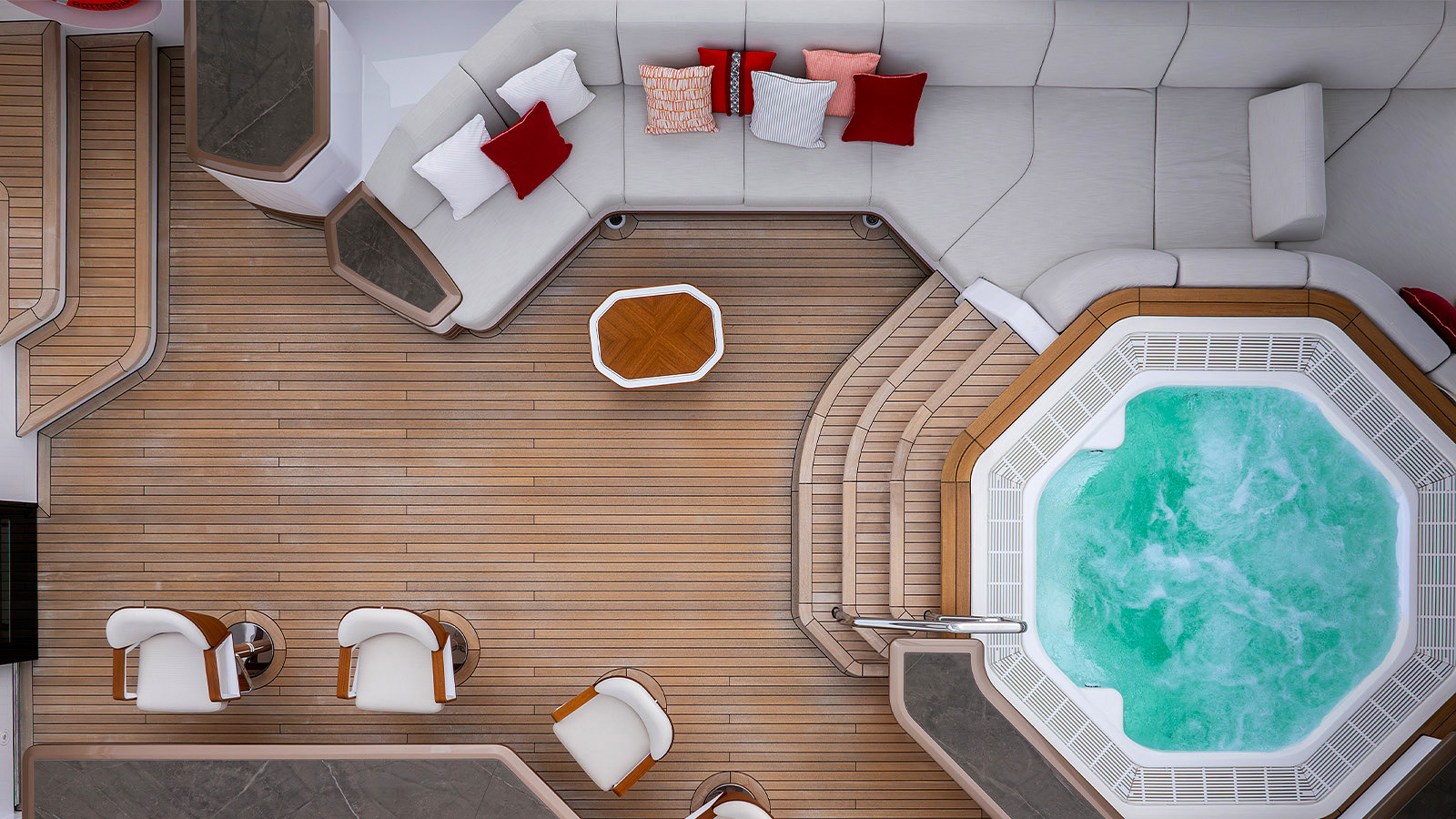 Aerial view of an elegant outdoor yacht deck featuring a circular seating area with white and red cushions, a central hexagonal wooden table, and an adjacent octagonal hot tub filled with bubbling water. The deck has two cushioned chairs and a wooden floor.
