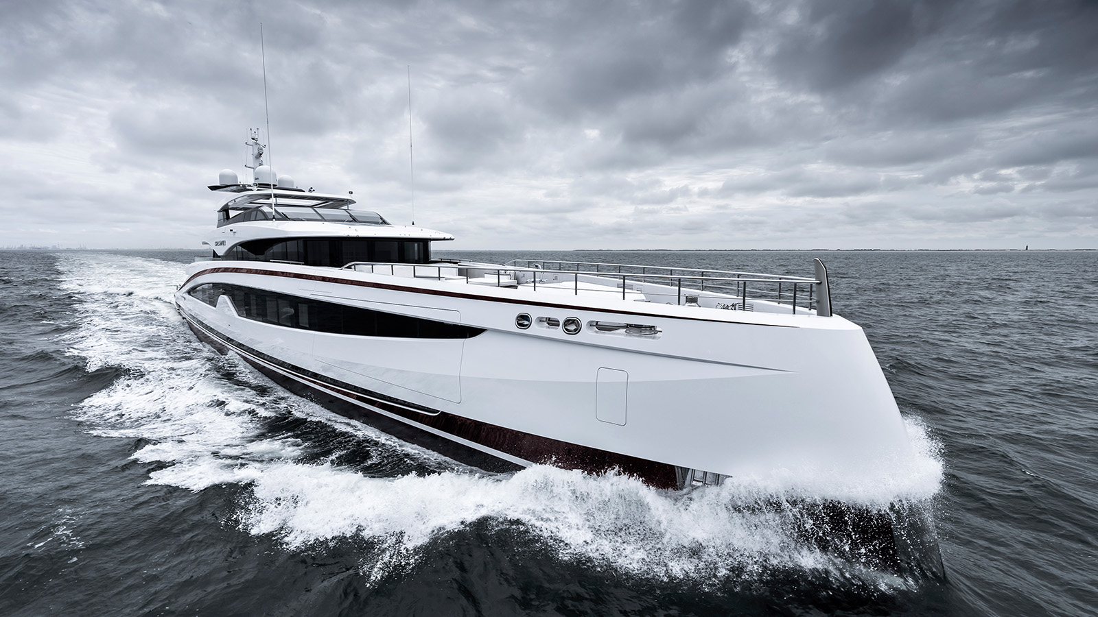 A sleek white luxury yacht cruising through the water with a cloudy sky overhead, creating waves as it moves forward.