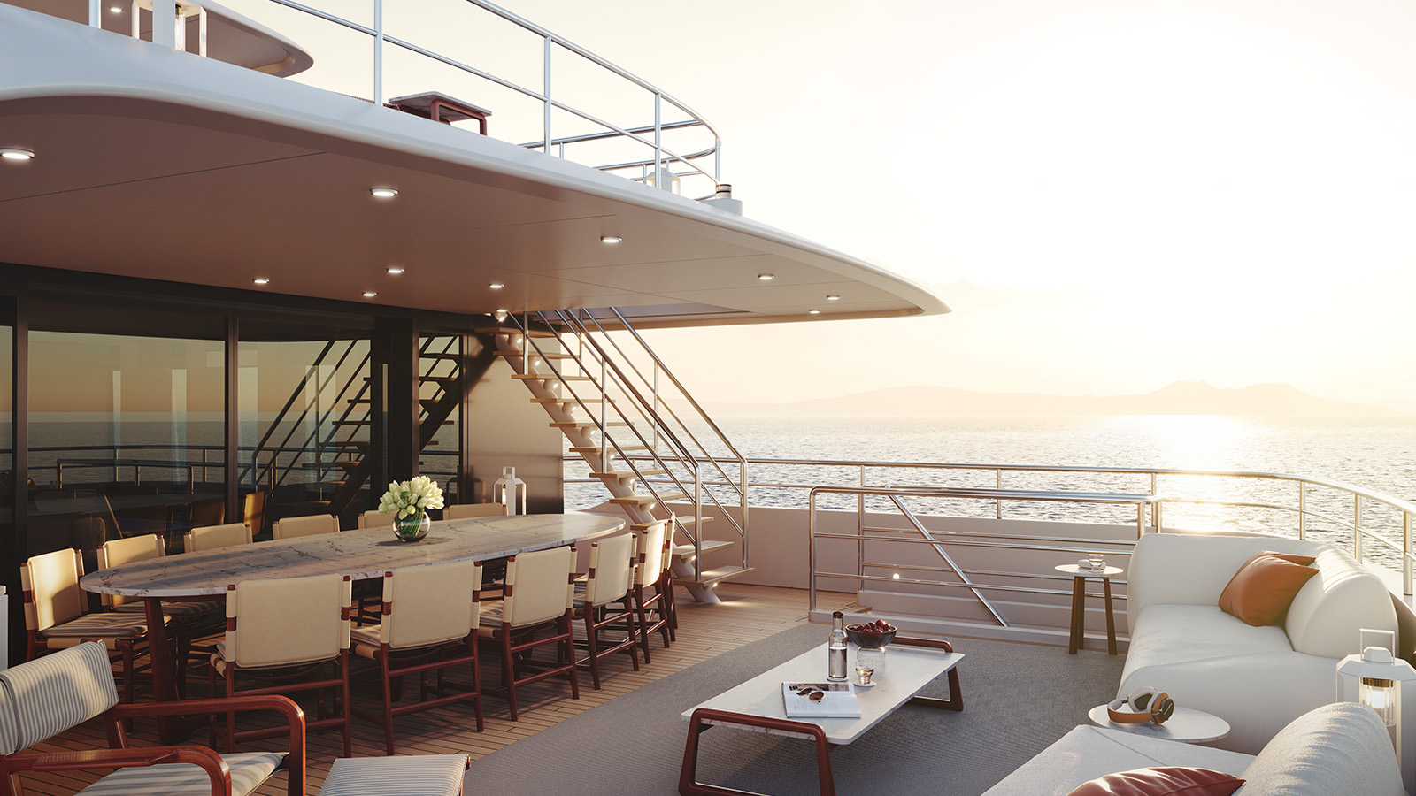 Luxurious deck of a yacht with a dining table, chairs, couches, and a view of the ocean during sunset.