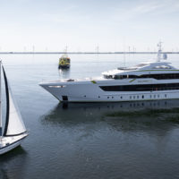 A large, modern yacht and a small sailboat named Giramondo on calm water, with wind turbines visible in the distance.