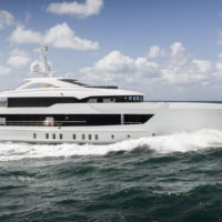 A large white luxury yacht cruising on the ocean under a partly cloudy sky.