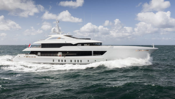 A large white luxury yacht cruising on the ocean under a partly cloudy sky.