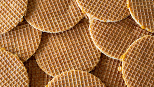 A close-up view of a pile of stroopwafels, showing their grid pattern and edges with sticky caramel filling.