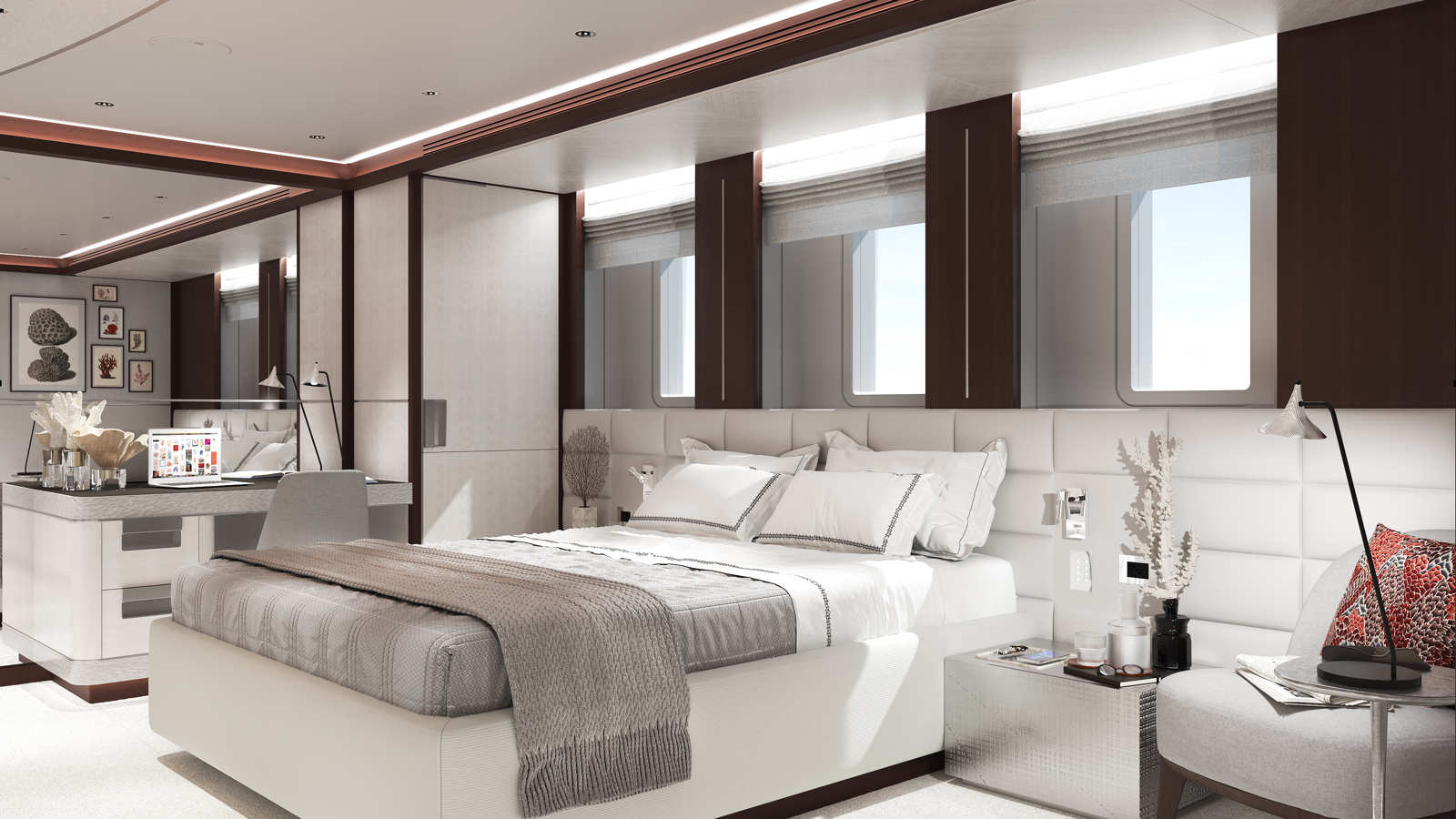 A luxurious bedroom with a modern design, featuring a neatly made bed with white and gray linens, a desk with a laptop, and artistic decor on the walls. Large windows provide natural light, and a cushioned chair with a lamp is situated near the bedside table.