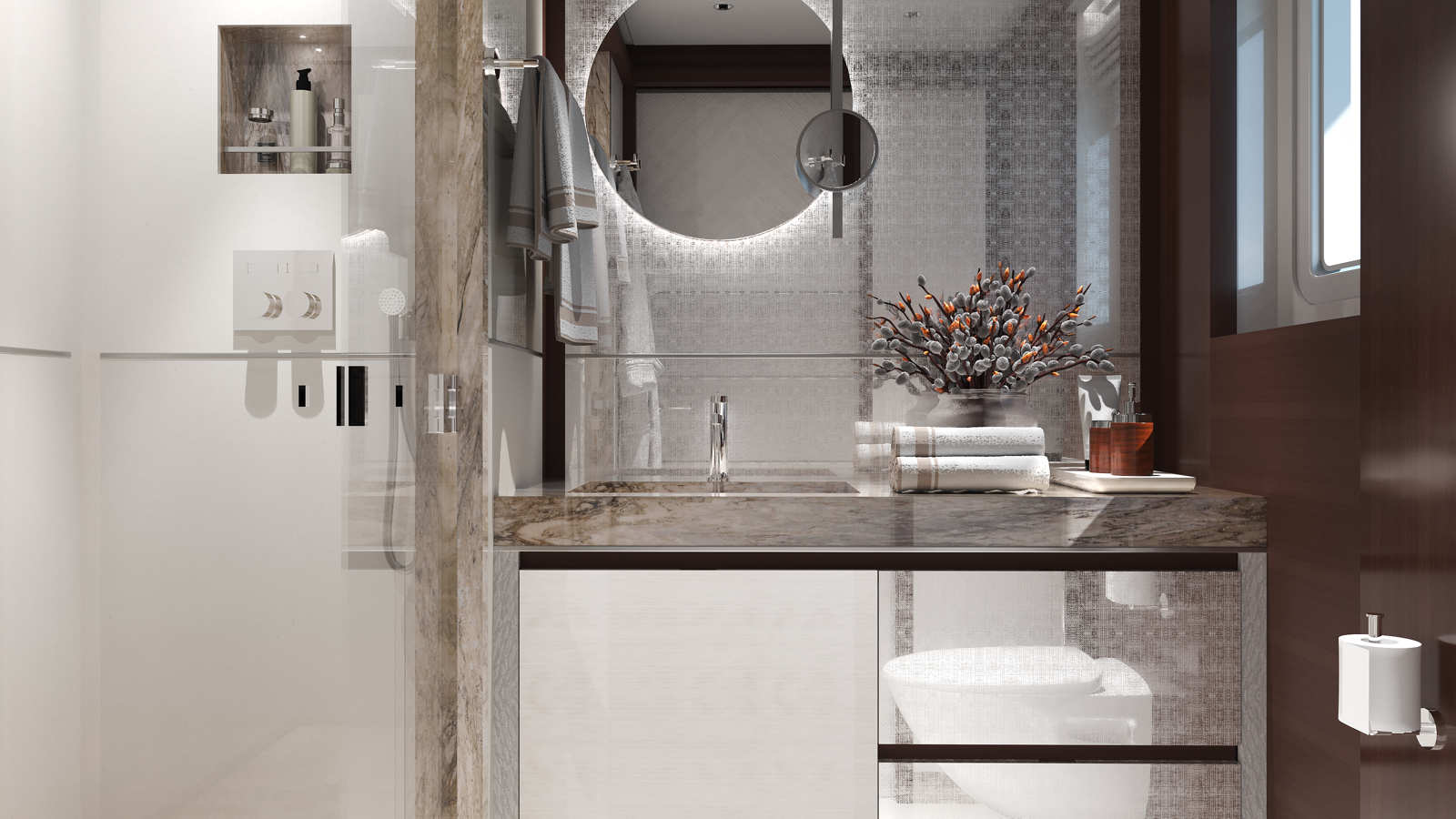 Modern bathroom interior with a large circular mirror, marble countertop, and a small vase holding decorative branches next to neatly folded towels. There is a glass shower enclosure on the left and a window on the right, providing natural light.